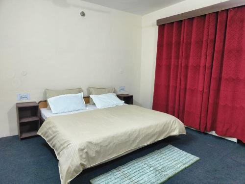 a bedroom with a large bed with a red curtain at The Kailasha Homestay in Nagar