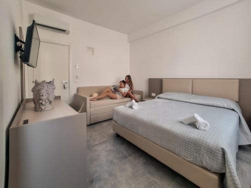 a woman sitting on a couch in a bedroom at La Regina d'Alabastro in Menfi