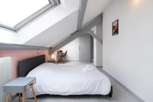 une chambre avec un lit blanc et une table dans l'établissement Le Havre Nancéien, à Nancy