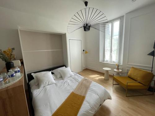 une chambre avec un lit blanc et une chaise dans l'établissement Studio centre au calme avec parking privé, à Cannes
