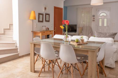 a living room with a dining room table and white chairs at Agrotospita Country Houses in Nafplio