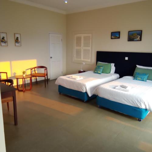 a bedroom with two beds and a table and a chair at Koh Ker Hotel and Restaurant in Phumĭ Mréch