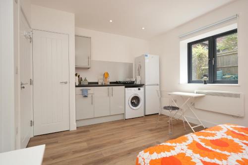 a white kitchen with a refrigerator and a table at Derwent Avenue self-contained apartments in Headington in Oxford