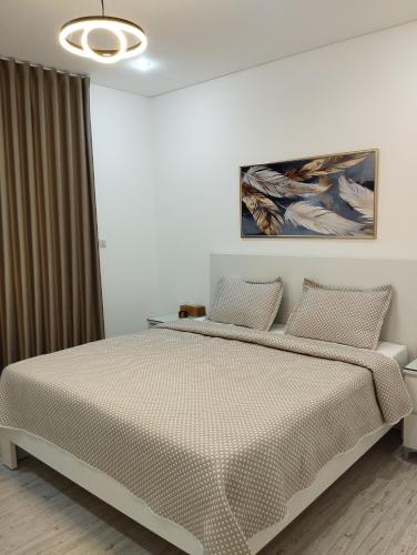 a bedroom with a bed and a painting on the wall at Airport chalet amman in Al Qasţal
