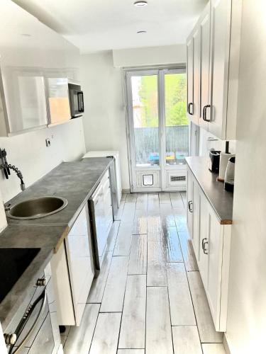 une cuisine blanche avec un évier et une fenêtre dans l'établissement Grand appartement proche palais, à Cannes