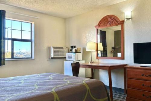 a hotel room with a bed and a desk and a mirror at Super 8 by Wyndham Colorado Springs/Afa Area in Colorado Springs