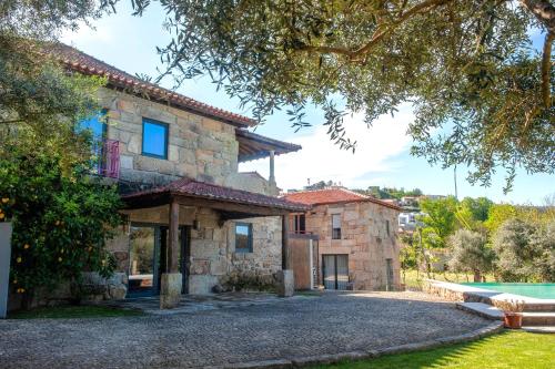 an exterior view of a stone house with a pool at Casa da Corredoura Turismo Rural in Celorico de Basto