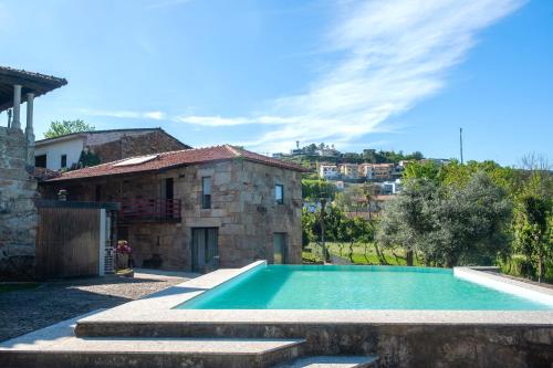 a swimming pool in front of a house at Casa da Corredoura Turismo Rural in Celorico de Basto