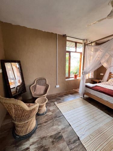 a bedroom with a bed and a tv and chairs at Dormigo in Bīr