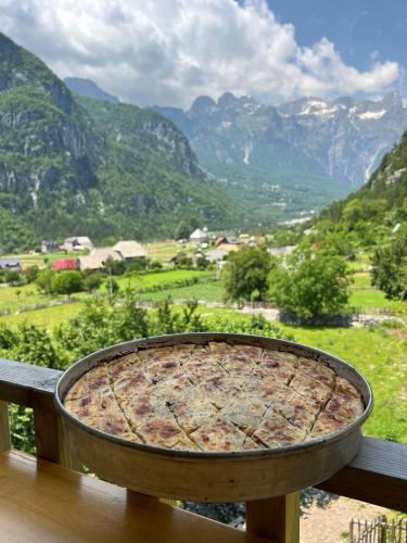 a pizza sitting on top of a balcony with mountains at Bujtina Ziçi in Theth