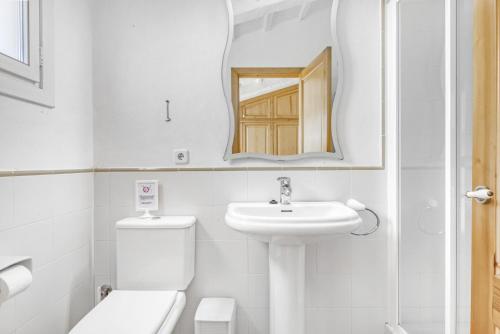 Un baño con lavabo, inodoro y espejo. en Finca Son Sanxo, en Alaior