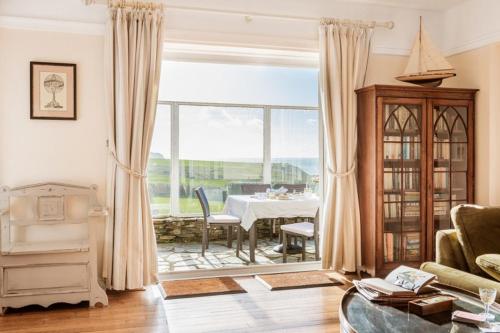 un salon avec une table et une grande fenêtre dans l'établissement Beachside, Luxury Cottage, Devon, à Thurlestone