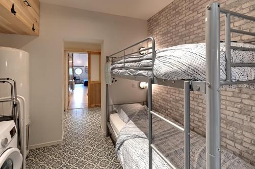 Dos literas en una habitación con una pared de ladrillo. en La Ligne Bleue des Vosges - Appt proche des pistes, en La Bresse