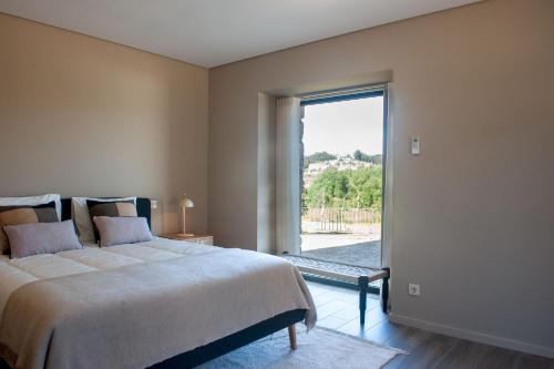 a bedroom with a large bed and a large window at Casa da Corredoura Turismo Rural in Celorico de Basto