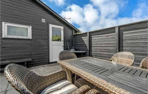 a patio with a wooden table and chairs at Two-Bedroom Holiday Home With A Fireplace In Rømø in Bolilmark