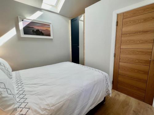 Un dormitorio con una cama blanca y una puerta de madera. en The Swallow's Nest, en Dingle