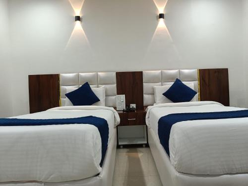 a hotel room with two beds with blue pillows at Hotel SkyLand in Warangal