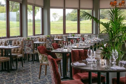 a dining room with tables and chairs and windows at Doubletree By Hilton Glasgow Westerwood Spa & Golf Resort in Cumbernauld