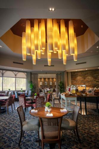 a restaurant with tables and chairs and a chandelier at Glasgow Westerwood Hotel, Spa & Golf Resort in Cumbernauld