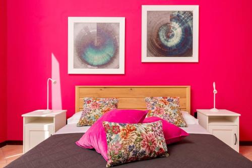 Un dormitorio con una pared rosa y una cama con almohadas en Vista San Domenico, en Palermo