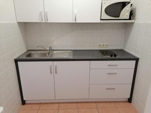 a kitchen with a sink and a microwave at apartmani Žganec in Baška