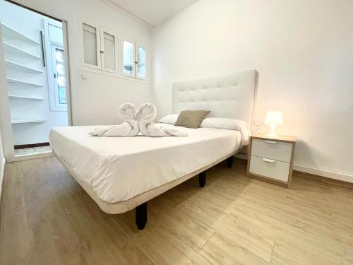 a bedroom with a white bed with a flower on it at Apartment Sanatori Beach, Barcelona in Calafell