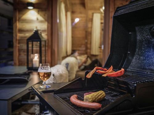 a grill with two hot dogs and a glass of wine at Aadla Walser-Chalets mit privater Sauna, Hotpot und Hotelservice in Schröcken