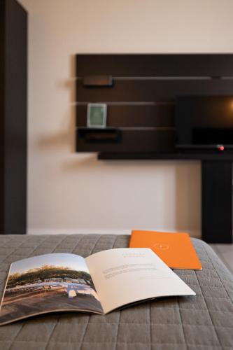an open book on a bed with an orange folder at Feudo Antico in Tollo