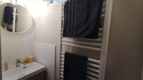 La salle de bains est pourvue d'un lavabo et d'une serviette noire. dans l'établissement Le Nid Douillet, à Clamart