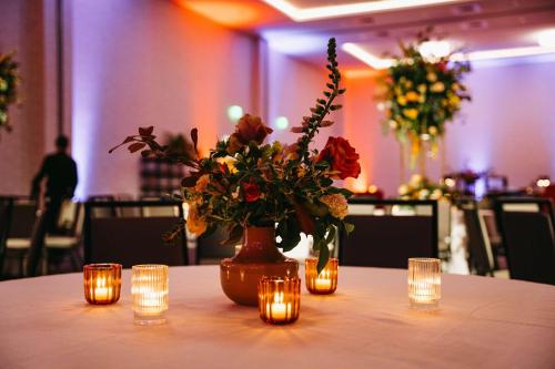 a vase with flowers and candles on a table with lights at Embassy Suites By Hilton Asheville Downtown in Asheville