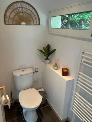 une salle de bain avec des toilettes blanches et une fenêtre dans l'établissement Échappée Mistral - Détente Jacuzzi privé & Brasero, à Eyragues