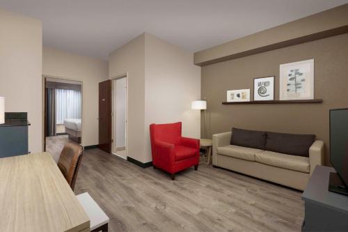 a living room with a couch and a red chair at Country Inn & Suites by Radisson, Gainesville, FL in Gainesville