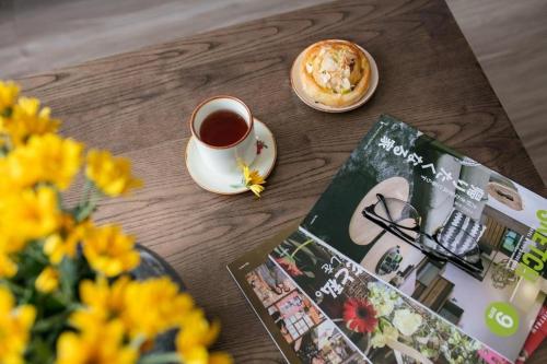 uma xícara de café e um livro sobre uma mesa com flores em The Bloom Pham Viet Chanh - Modern Living Space in Saigon - A Top Choice for Western Travelers em Cidade de Ho Chi Minh