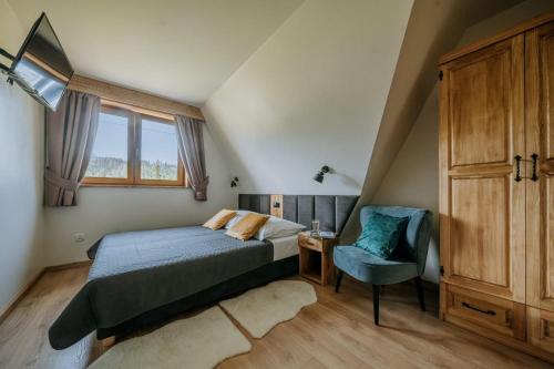 a bedroom with a bed and a chair and a window at Domek z kominkiem i sauną w górach - Domek Pod Jeziorem in Murzasichle