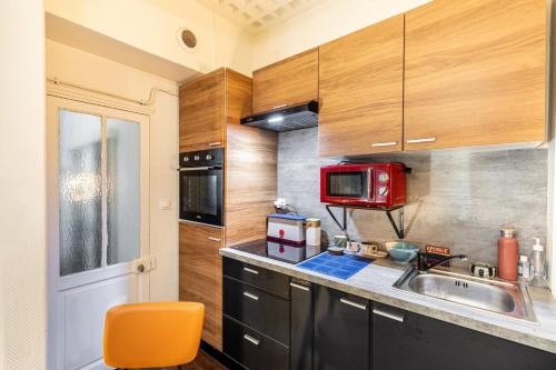 La cuisine est équipée d'un évier et d'un four micro-ondes rouge. dans l'établissement GuestReady - Funky Galileo perto do Canal St Martin, à Paris