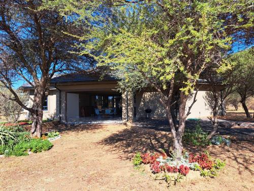 a house with trees and flowers in a yard at Bushveld Magic in Klipdrift