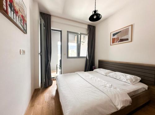 a bedroom with a bed with white sheets and windows at Mediterranean Apartment 2 in Budva