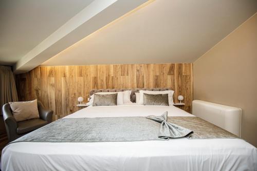 a bedroom with a large bed and a chair at Les Clarisses Boutique Hotel in Vic