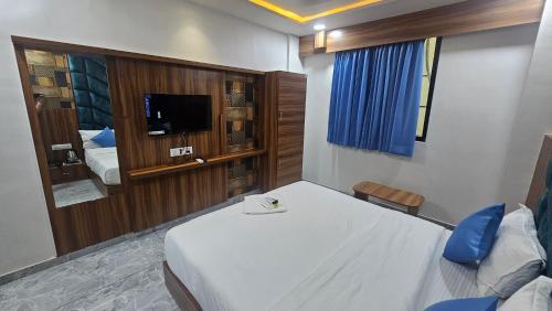 a bedroom with a large white bed and a tv at Hotel SERENE STAY in Surat