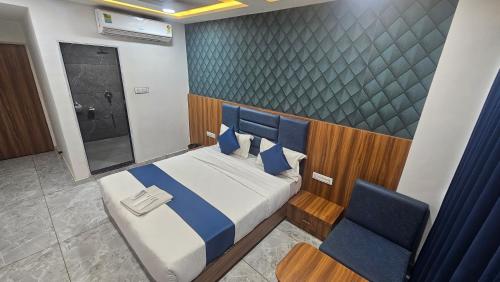 a bedroom with a bed and two blue chairs at Hotel SERENE STAY in Surat