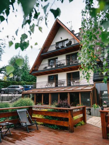 a building with a deck and chairs in front of it at Willa Pachówka - tam, gdzie natura spotyka się z nowoczesnością in Bukowina Tatrzańska