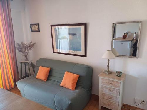 - un salon avec un canapé bleu et deux oreillers orange dans l'établissement Appartement Port Grimaud, à Grimaud
