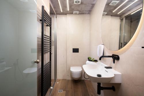 a bathroom with a sink and a toilet and a mirror at Tsikeli Boutique Hotel Meteora - Adults Friendly in Kalabaka