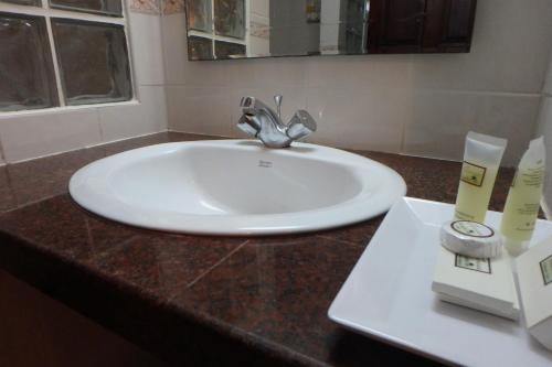 lavabo blanco en el baño con espejo en Paradise Inn en Karon