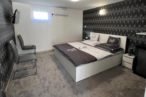 a bedroom with a bed and a chair in it at Adél Apartman in Kisújszállás