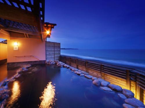 a hotel pool with the ocean in the background at Kamogawa Grand Hotel in Kamogawa