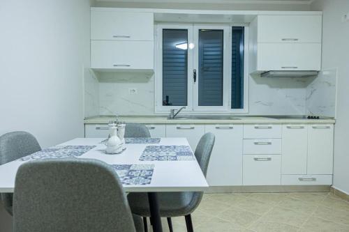 Una cocina con una mesa y sillas y un fregadero. en Premium Beach Apartments Jonufer, en Vlorë