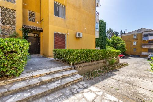 a yellow building with stairs leading to a door at Eirini's Apartment in Kanoni
