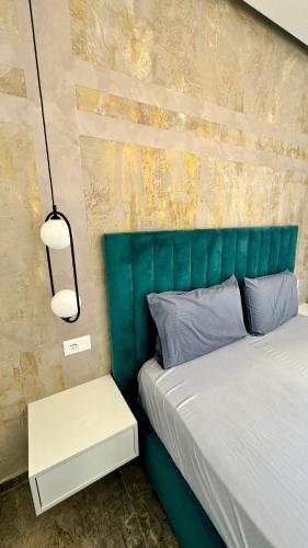 a bed with a green headboard with a night stand next to it at Heaven Apartment Drimades Olea Residence in Gjilek
