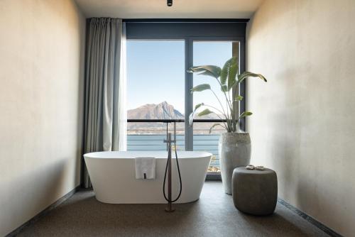 a bathroom with a tub and a large window at Cape of Senses in Torri del Benaco